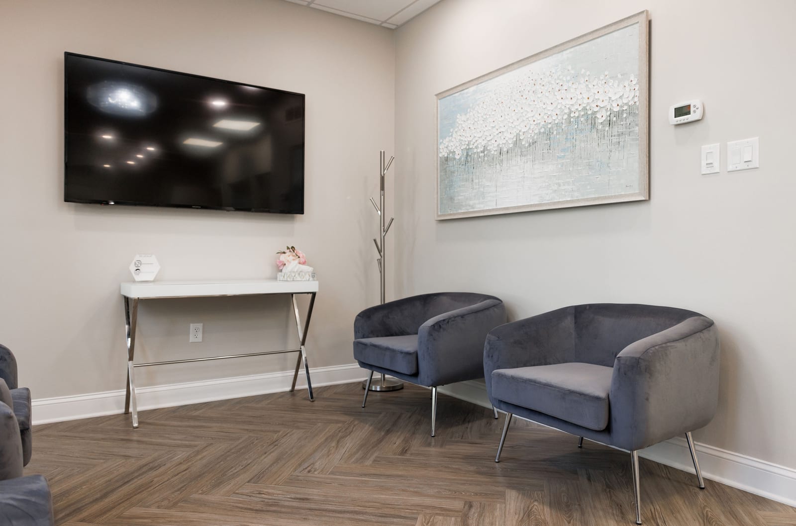 Waiting area at Inna Vinnikov, DMD: grey velvet chairs, herringbone floor, abstract painting